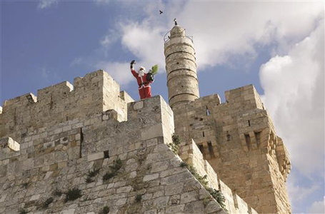 فلسطيني يرتدي زي «سانتا كلوس» يقف على أحد أبنية المدينة القديمة في القدس المحتلة أمس (أ ف ب)