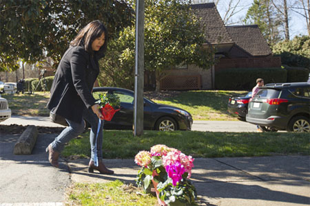 A man places flowers near a building where three young Muslims were killed on Tuesday, in Chapel Hill, North Carolina February 11, 2015. (Reuters / Chris Keane)