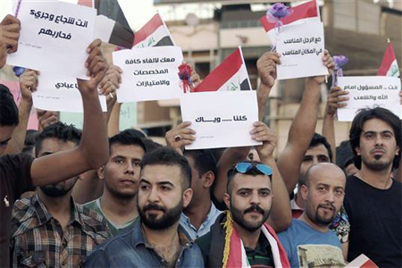 متظاهرون عراقيون يرفعون شعارات مؤيدة لخطوات العبادي في ساحة التحرير في بغداد، امس (أ ف ب)