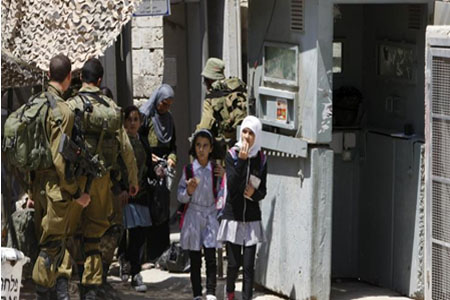 تلميذات فلسطينيات عند نقطة تفتيش إسرائيلية لدى عودتهن من المدرسة بمدينة الخليل في الضفة الغربية (رويترز)