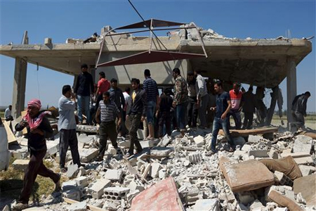 شبان يتفقدون مبنى دمر بغارة جوية في قرية العجمي في ريف درعا امس (رويترز)